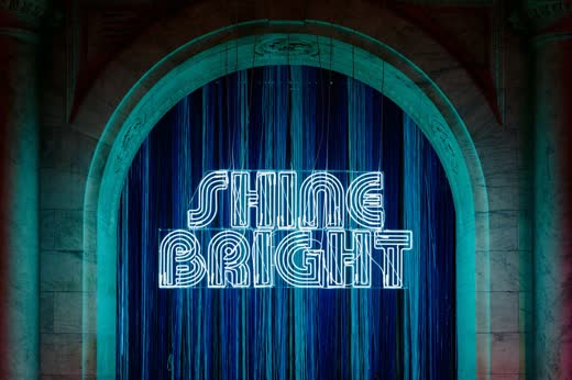 A neon Shine Bright sign on a velvet stage at The Knot Gala
