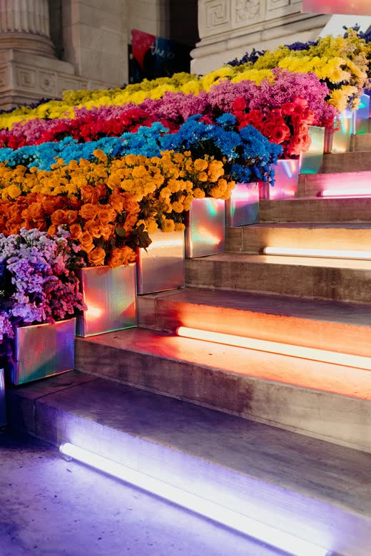 Library stairs lined with flowers and rainbow light at The Knot Gala
