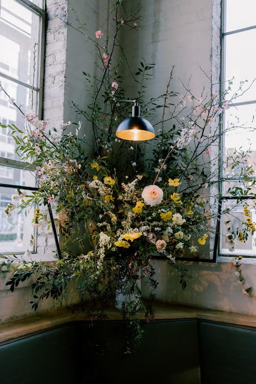 A tall spring arrangement beside a factory window