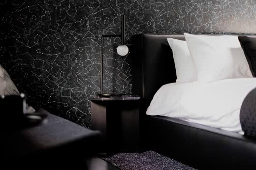 A black bedroom with textured black walls and white linen