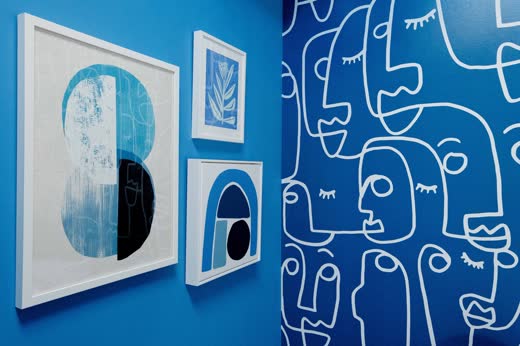 Blue framed prints over a matching mural
