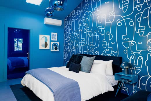 A cobalt bedroom with a white line-drawn mural