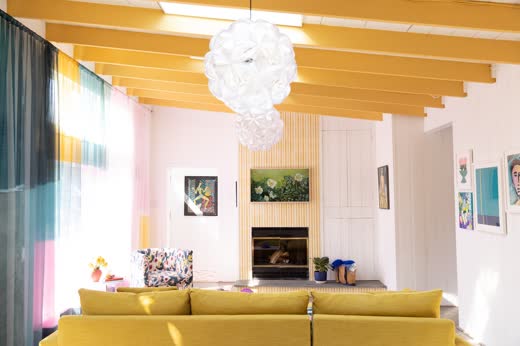A living room with a mustard sofa under yellow beams