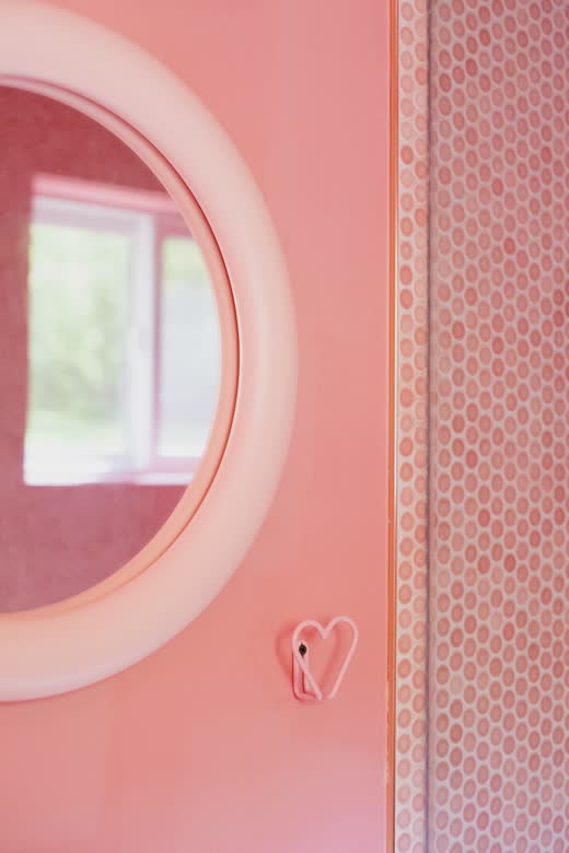 A round window cut into a pink wall