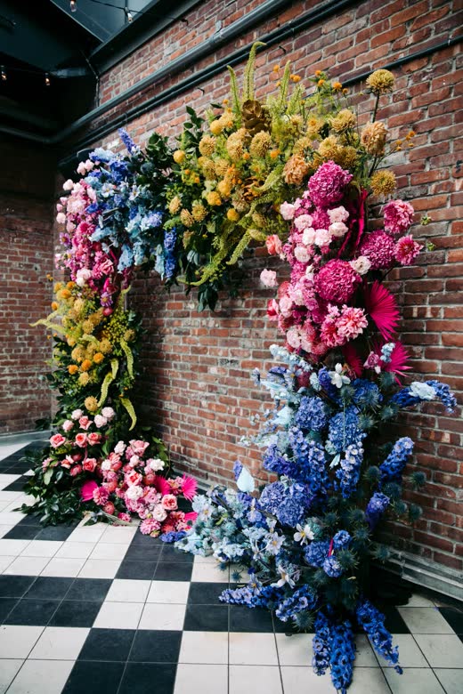 A wedding couple under an arch of bright flowers